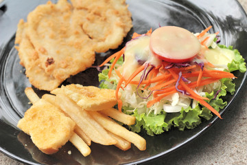 fish steaks and vegetable salad with french fries.