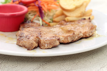 steaks and vegetable salad with french fries.