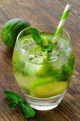 mojito cocktail and fresh ingredients on brown wooden table
