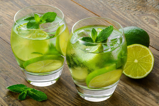mojito cocktails and fresh ingredients on brown wooden table