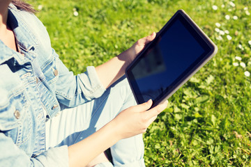 close up of girl with tablet pc sitting on grass
