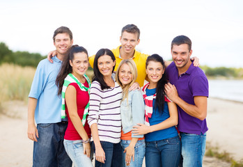 Obraz premium group of happy friends hugging on beach