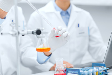 close up of scientists filling test tube in lab