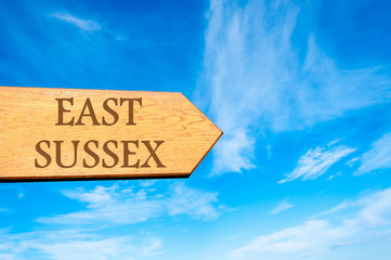 Wooden arrow sign pointing destination EAST SUSSEX, ENGLAND