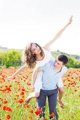 Happy girl and boy on a meadow full of poppies