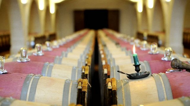 Defocus on row of wood barrels in a wine cellar with candle.