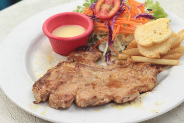 steaks and vegetable salad with french fries.