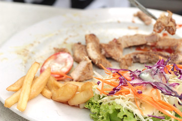 steaks and vegetable salad with french fries.