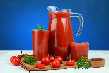 A glass of tomato juice and fresh tomatoes on a wooden table