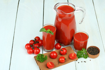 A glass of tomato juice and fresh tomatoes on a wooden table