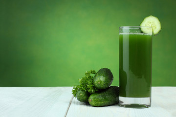 A glass of cucumber juice and fresh cucumber on a wooden table