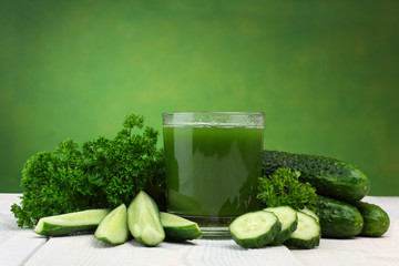 A glass of cucumber juice and fresh cucumber on a wooden table