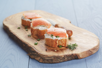 small sandwiches with soft cheese and salmon on wood table