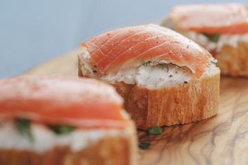 small sandwiches with soft cheese and salmon on wood table