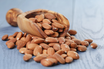 roasted almonds in measuring scoop on blue wooden table