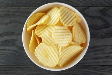 rippled organic chips in white bowl on wooden table