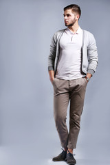 Fototapeta premium Stylish young man in casual attire posing with hands in pockets, modern fashion and lifestyle portrait