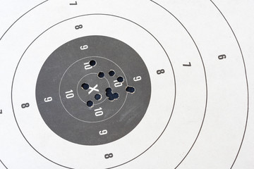 Close up of a shooting target and bullseye with bullet holes.