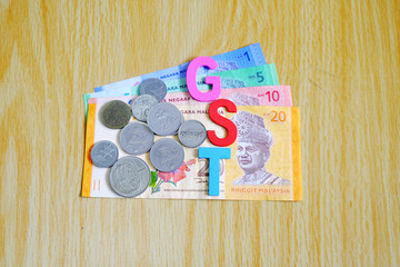 GST or Goods and Services Tax alphabet letters with Malaysian currency and Background texture of wood. Concept of Government Service Tax.
