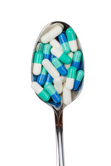 Green pilules in the spoon, isolated. Healthcare concept.