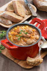 delicious vegetable stew with sausages in a pan, vertical 