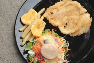 fish steaks and vegetable salad with french fries.