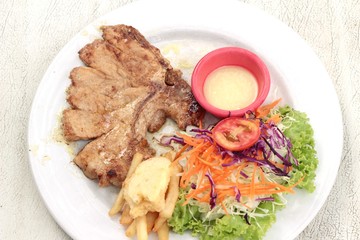 steaks and vegetable salad with french fries.
