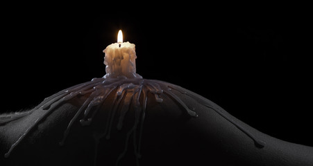 Body scape of a well-shaped woman with burning candle and wax on