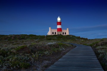 Fototapeta na wymiar Lighthouse shining light in darkness with dark blue clouds