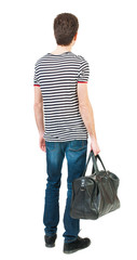 Back view of man in jeans with bag in his hand.