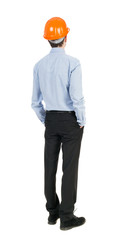 Backview of an engineer in construction helmet stands.