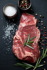 Close-up of raw fresh ribeye steak with seasonings, studio shot