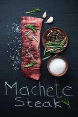 Raw machete beef steak with various herbs and spices, above view