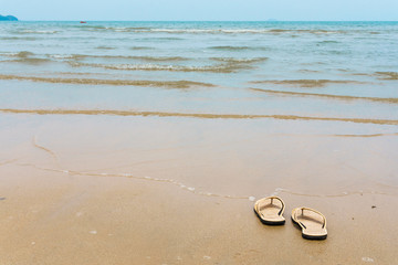 Fototapeta na wymiar slipper on sand beach and wave see