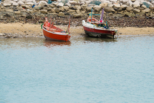 small fishing boats float on see near cement breakwater