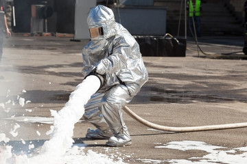 Naklejka premium Firemen spray firefighting foam