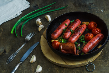 grilled sausages with vegetables in a frying pan