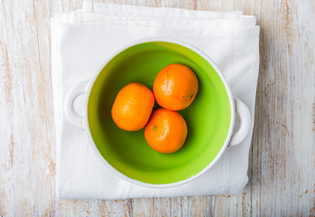 Tangerines in a bowl on a white wood