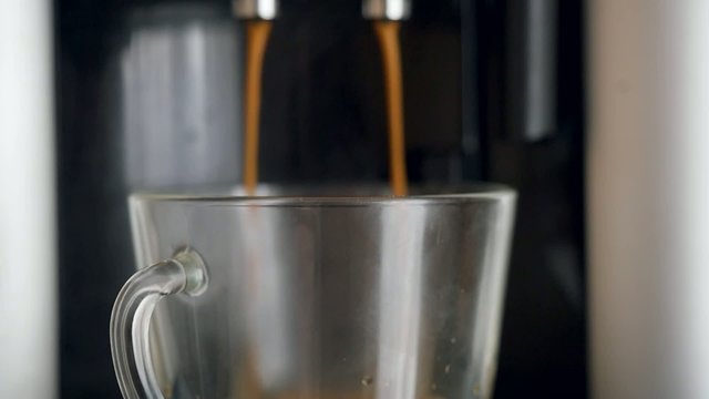 coffe dispenser with cup of coffee. Slowmotion pour