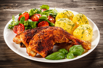 Barbecued chicken legs with boiled potatoes and vegetables 
