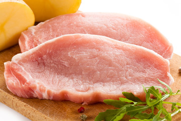 Raw pork chops on cutting board on white background