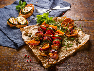 Grilled sausage and vegetables skewers with fresh herbs