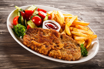 Fried pork chop, French fries and vegetable salad 