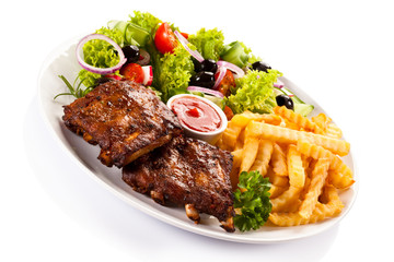 Grilled ribs, French fries and vegetables on white background