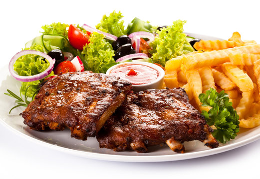 Grilled ribs, French fries and vegetables on white background