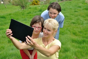 Fototapeta premium Family sitting on the lawn and using digital tablet