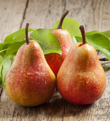 Fresh pink pear with drops of water on wooden table, selective f