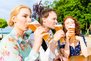 Frau trinkt mit Freunden Bier im Biergarten 
