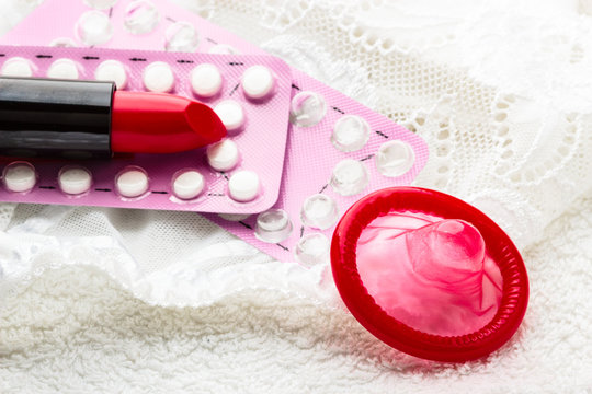 Pills condom and lipstick on lace lingerie.