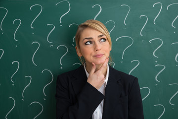 Contemplated Businesswoman In Front Of Chalkboard